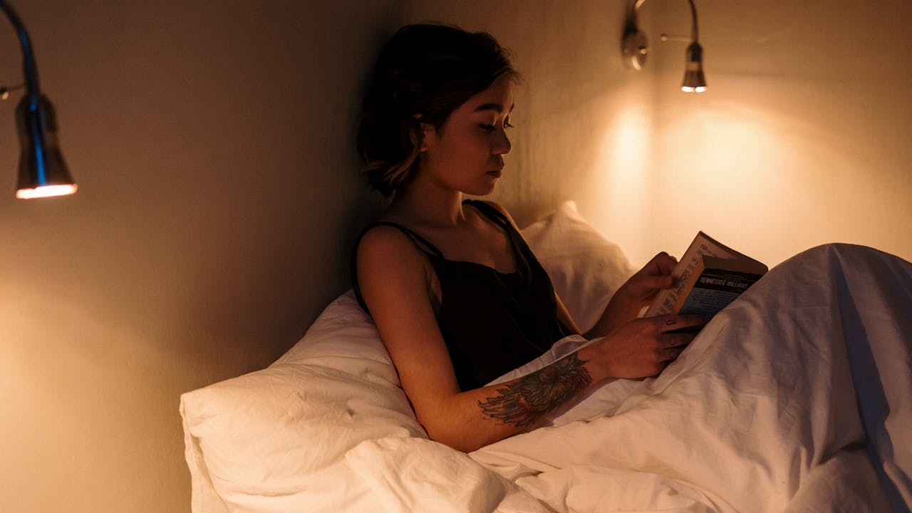 夜にベッドで本を読む女性、リラックスした充実した時間