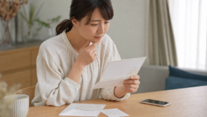 結婚式の招待状を見て欠席を迷う人のイメージ