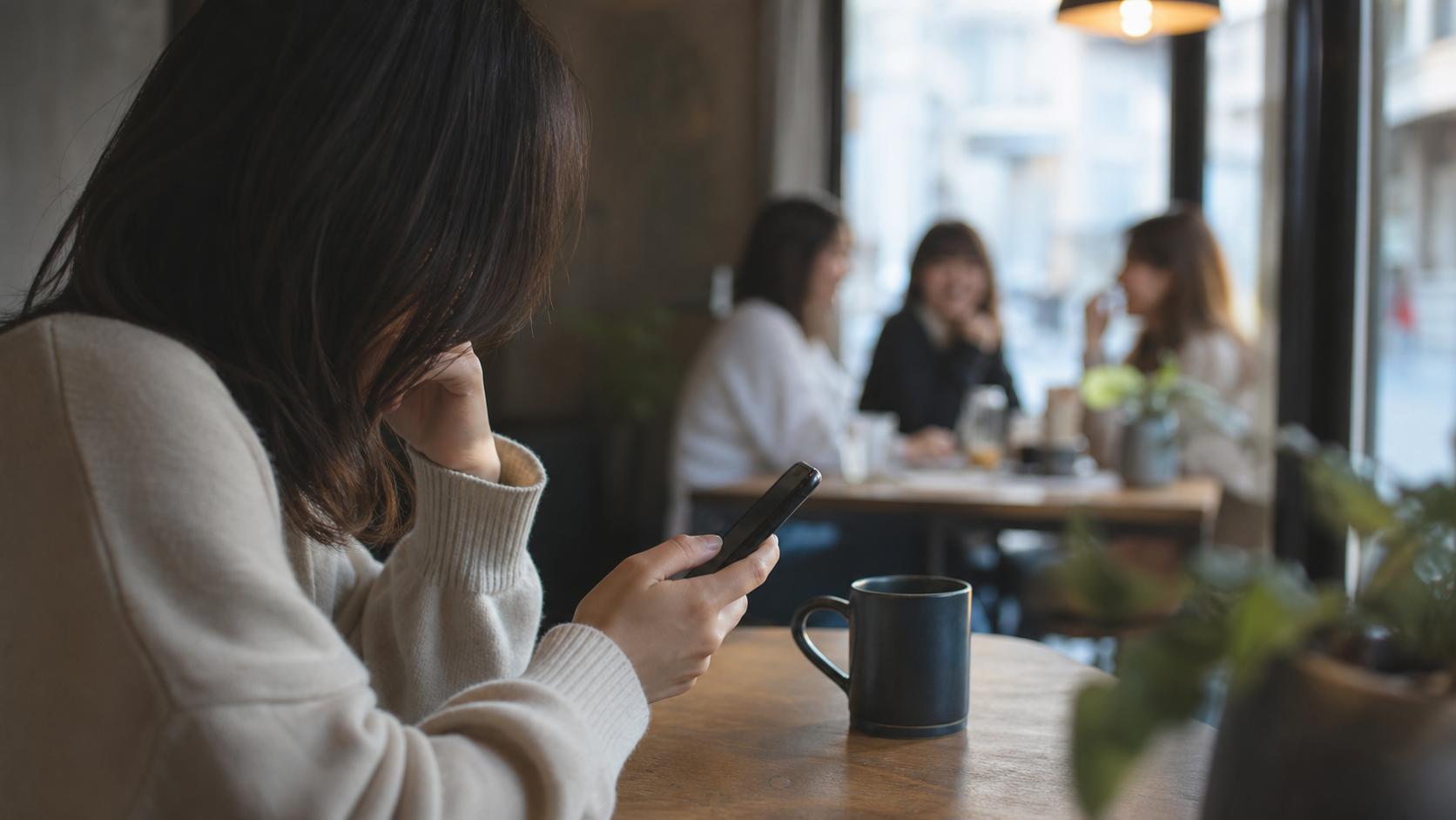 カフェでスマホを見ながら他人と比べてしまう心理のイメージ