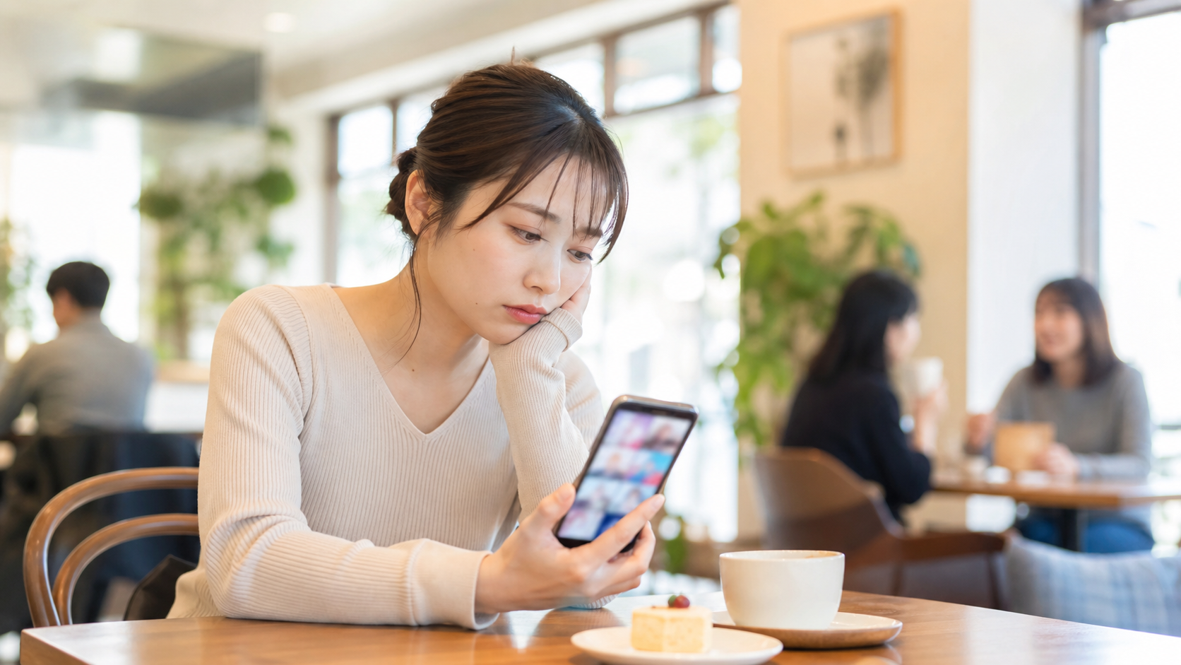 リア充に見える投稿と本音のギャップで疲れた人がカフェでスマホを見る様子