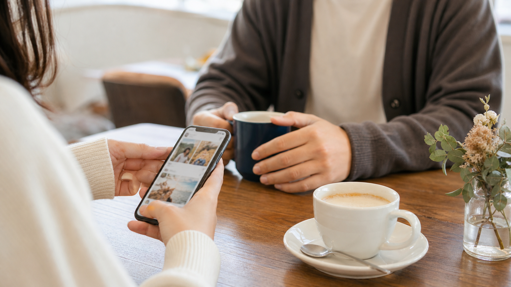 カフェでSNS投稿を見ながら会話する恋愛シーンのイメージ