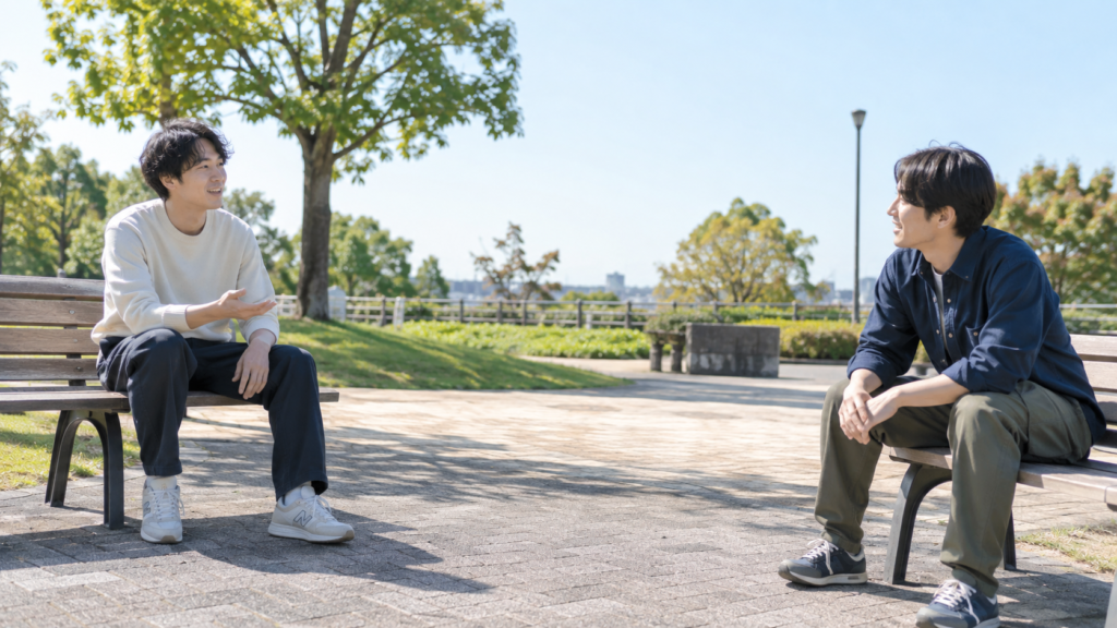 公園の椅子に座って落ち着いて話す二人の友達