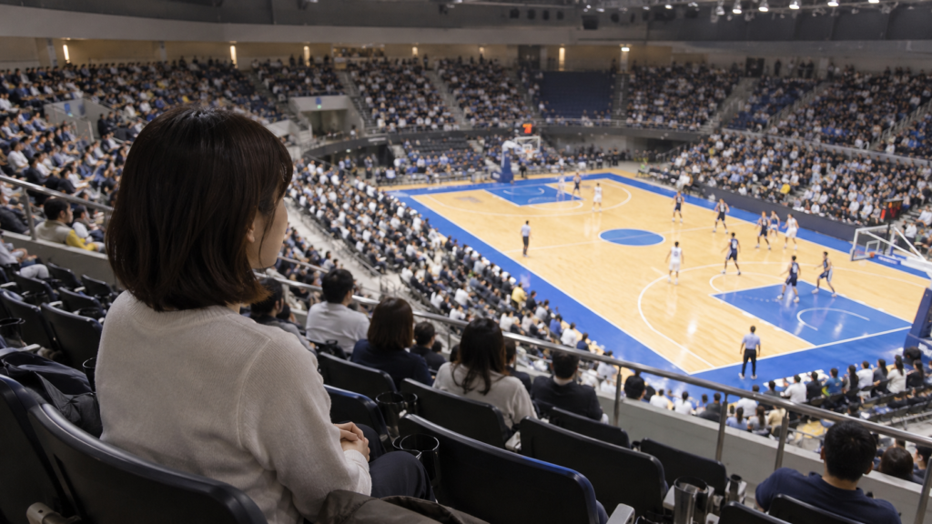 屋内のバスケットボール会場で一人で試合を見る人のイメージ