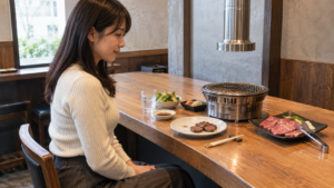 一人用の席で焼肉を楽しむ成人と小さなロースター
